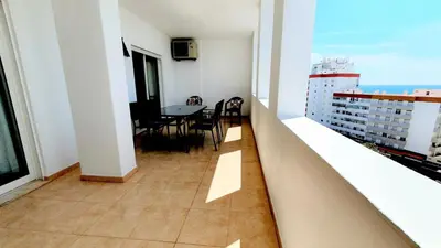 a balcony with a table and chairs in a building at Quarteira Beach Vacation: 2BR steps to the sand in Quarteira