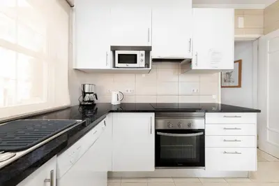 a kitchen with white cabinets and a black appliance at Villa Farol by OCvillas in Galé