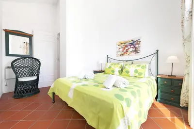 a bedroom with a bed with a yellow blanket and a chair at Villa Farol by OCvillas in Galé