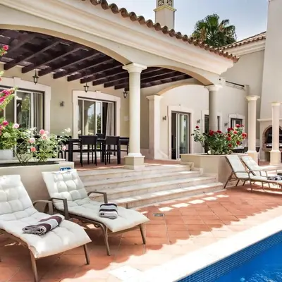 an outdoor patio with white chairs and a pool at Villa Millennium luxury villa relaxing location in Almancil
