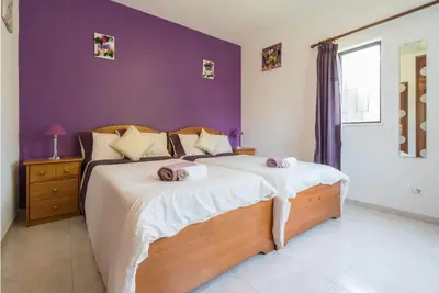 a bedroom with a large bed with a purple wall at Villa Alegria in Loulé