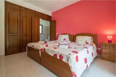 a bedroom with a large bed with a red wall at Villa Alegria in Loulé