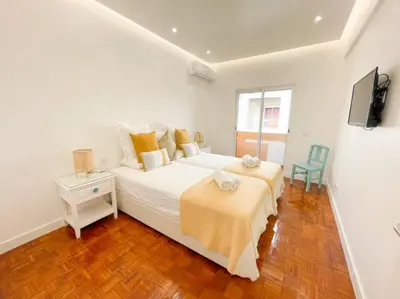 a white bedroom with a bed and a chair at So Sweet Center of Faro Flat in Faro