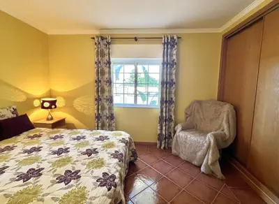 a bedroom with a bed and a chair and a window at Vila Caravela - Private Pool by HD Properties in Vilamoura