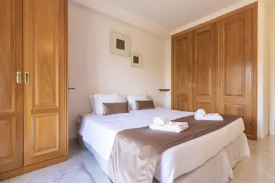 a bedroom with a large white bed with wooden cabinets at Apartamento King in Vilamoura