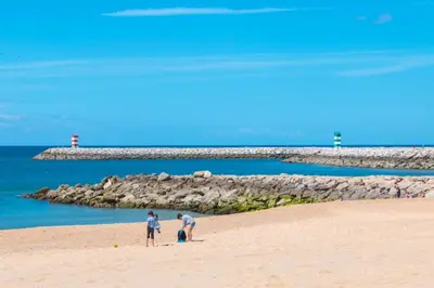 a group of three people standing on a beach at Apartamento Alameda in Quarteira