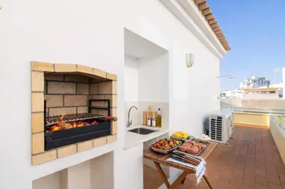 a outdoor kitchen with a fireplace on a balcony at Apartamento Alameda in Quarteira