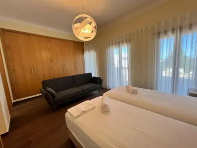 a hotel room with two beds and a couch at Villa Pedra Luxe - Spacious modern villa in Albufeira