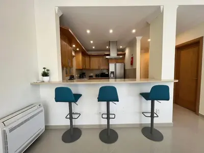 a kitchen with three blue stools at a counter at Villa Pedra Luxe - Spacious modern villa in Albufeira