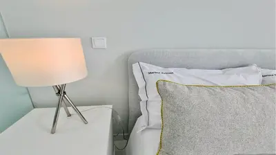 a lamp next to a bed with a pillow at Marina Retreat - CleverDetails, for 2 adults and 2 children, Jacuzzi, near the Marina and the beach in Vilamoura