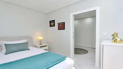 a white bedroom with a bed and a door to a bathroom at Marina Retreat - CleverDetails, for 2 adults and 2 children, Jacuzzi, near the Marina and the beach in Vilamoura