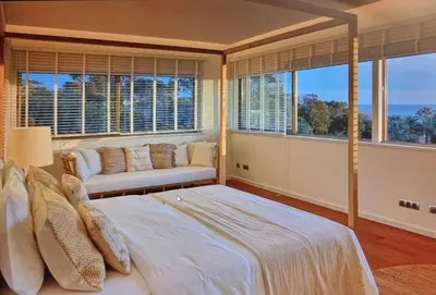 a bedroom with a bed and a couch and windows at Luxury Beach Villa - Casa do Forte- Infinity Pool sea view- Beach walking distance by DreamvillasAlbufeira in Albufeira