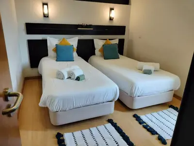 two beds in a room with white sheets and blue pillows at Vilamoura Apartamento Algarve 311 in Vilamoura
