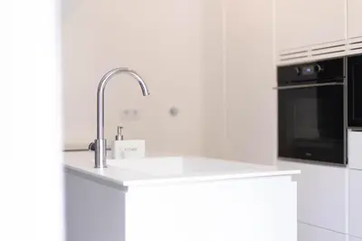 a white kitchen with a sink and a microwave at Orange Boutique Residence - Casa Luis Camões in Quarteira