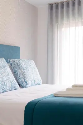 a bedroom with a bed with blue pillows and a window at Orange Boutique Residence - Casa Luis Camões in Quarteira