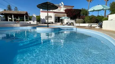 a large swimming pool with an umbrella in front of a house at Nicola by Check-in Portugal in Albufeira