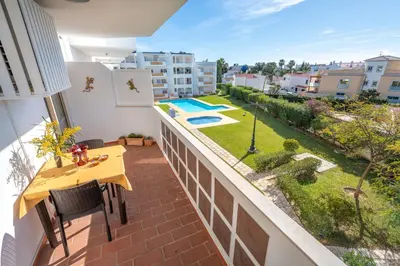 a balcony with a table and a swimming pool at AlgarSun - idealy situated holiday apartment with all modern comfort in Albufeira