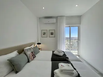 a white bedroom with a large bed and a window at Faro Deluxe by Homing in Faro
