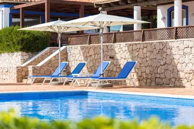 a group of chairs and umbrellas next to a swimming pool at Shantivillas Malhão in Azinhal