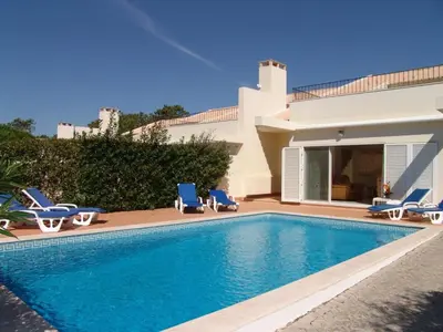 a swimming pool with chairs and a house at Villa Bonsal - Modern villa in a prime location near the luxury golf courses in Albufeira