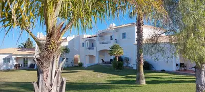 a large white house with palm trees in front of it at Baia Village - Galé - Albufeira in Albufeira