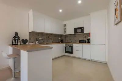 a white kitchen with white cabinets and a counter at Lemon House - 400m from the Beach - Wifi in Albufeira