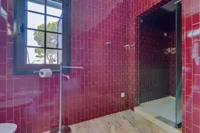a red tiled bathroom with a toilet and a window at Vila Alice in Quarteira