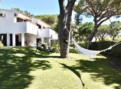 a hammock hanging from a tree in front of a house at Vila Alice in Quarteira