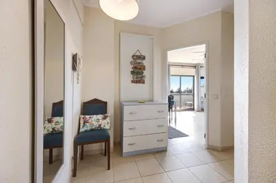 a bedroom with a dresser and a chair and a mirror at House Amendoeiras in Vilamoura