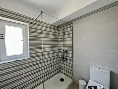 a bathroom with a shower and a toilet and a window at Vilamoura Central 5 by Homing in Vilamoura