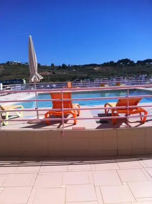 a swimming pool with three chairs and an umbrella at Marina de Albufeira T2 até 6 pax Com Piscina e Vista Marina in Albufeira