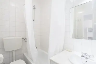 a white bathroom with a toilet and a sink at Bright 2BR Apartment with Private Balcony - Albufeira Beach, by Hopstays in Albufeira