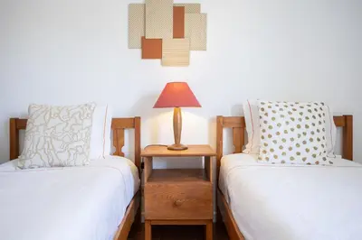 a white bedroom with a blue bed and a chair at Bright 2BR Apartment with Private Balcony - Albufeira Beach, by Hopstays in Albufeira