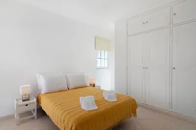 a white bedroom with a bed with a yellow blanket at Villa Galé in Guia