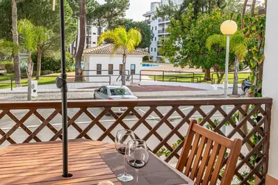 a table with two wine glasses on a balcony at BeGuest Falésia Pine & Sun Apartment in Albufeira