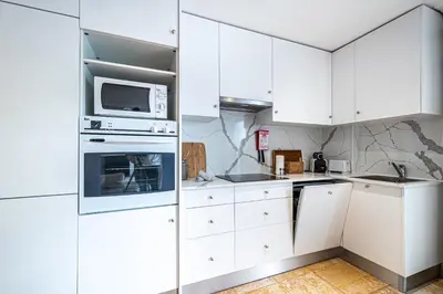 a white kitchen with white cabinets and a microwave at BeGuest Falésia Pine & Sun Apartment in Albufeira
