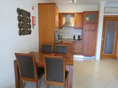 a kitchen with a wooden table and chairs and a kitchen with a kitchen at Apartamento - CERRO MAR in Albufeira