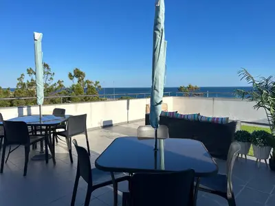 a patio with tables and chairs and the ocean at Blue Wave Apartment in Albufeira