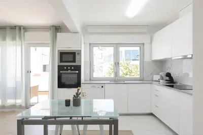 a kitchen with white cabinets and a glass table at Miral Beachside 5 - by HD Properties in Albufeira