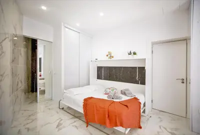 a white room with a bed with an orange blanket on a table at Dubai Apartment in Albufeira