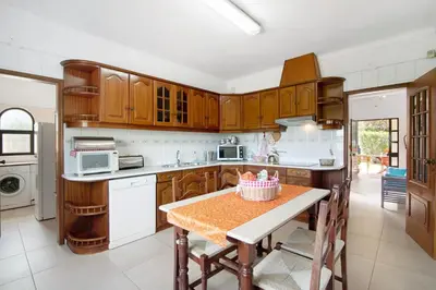 a kitchen with wooden cabinets and a table at Casa da Oliveira in Loulé