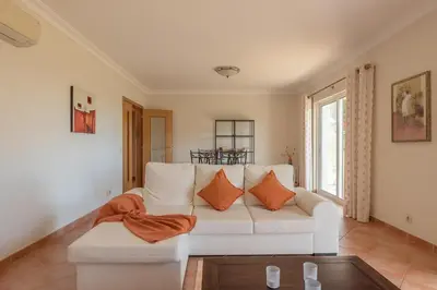 a living room with a white couch with orange pillows at Villa Castelo Beach - Cosy modern - 500m from Castelo beach in Albufeira