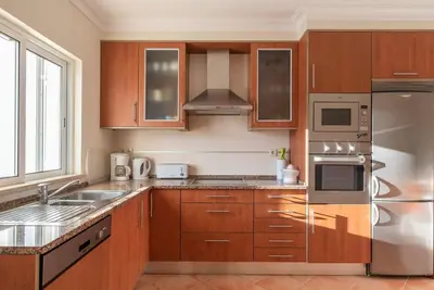 a kitchen with wooden cabinets and stainless steel appliances at Villa Castelo Beach - Cosy modern - 500m from Castelo beach in Albufeira