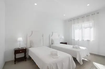 a white room with two beds with white sheets at Casa da Letinhas in Albufeira