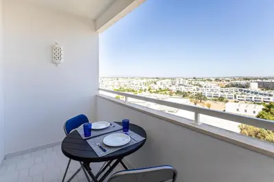 a small table and chairs in a room with a large window at The Albufeira Concierge - Pool & Sunset Balconies in Albufeira