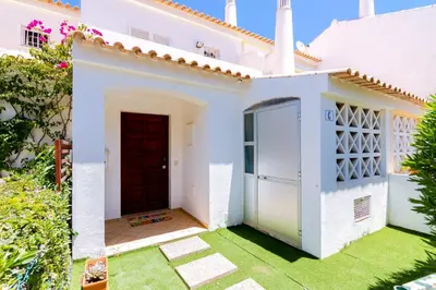 a white house with a red door and a yard at Small Villa 4Pax -Shared Pool @ Homesbyfc in Albufeira