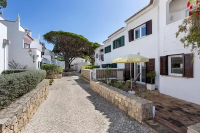 a house with a stone retaining wall and an umbrella at Villa Isabel in Vale do Lobo