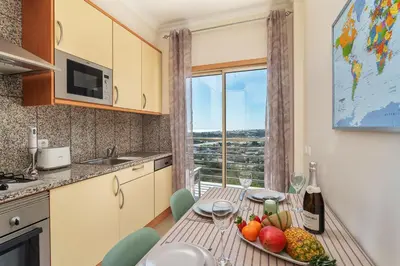 a balcony with a chair and an umbrella and the ocean at BnB Homes Ocean View Apartment with relax Terrace, 2 Swimming pools & Tennis court in Albufeira