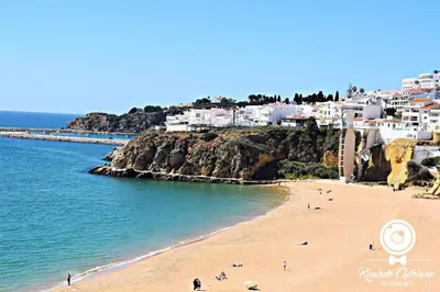 a beach with people on the sand and buildings at Casa Alfarroba in Albufeira