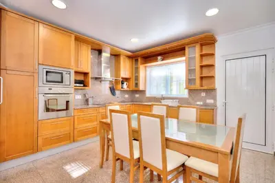 a kitchen with wooden cabinets and a table and chairs at Amora Classic Villa in Vilamoura
